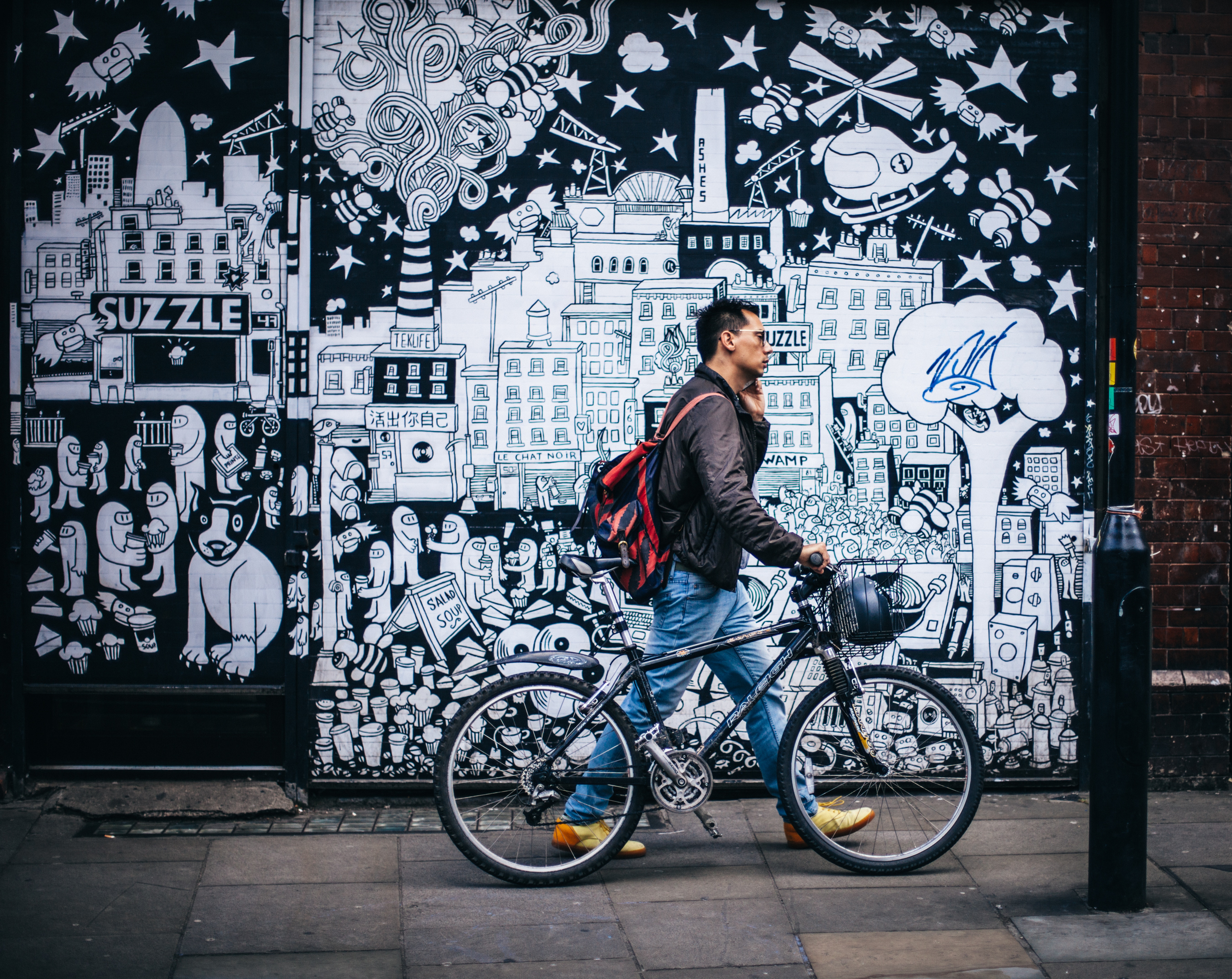 man on phone walking in front of elaborate street mural