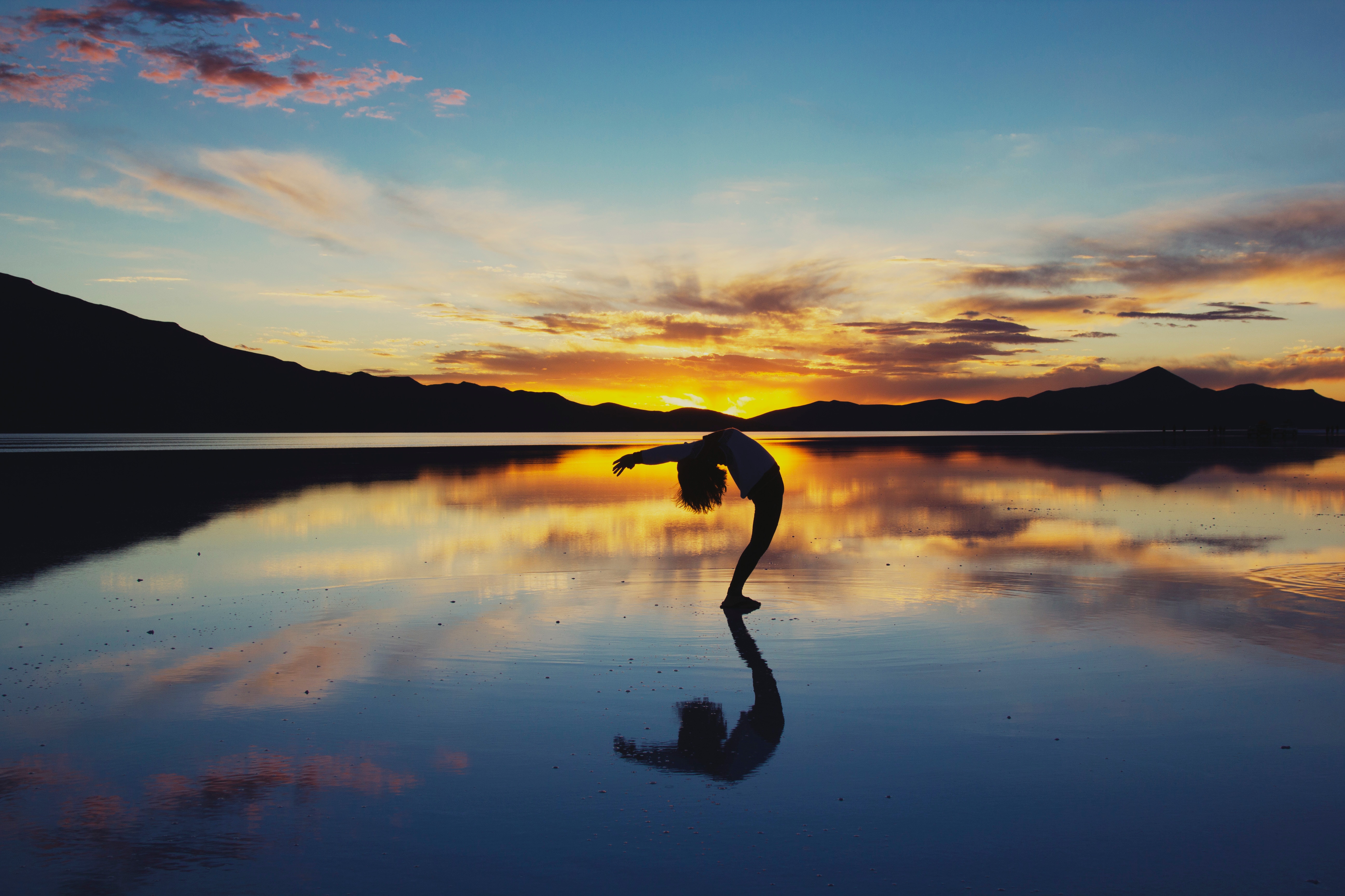 a silhouetted woman doing yoga at sunset